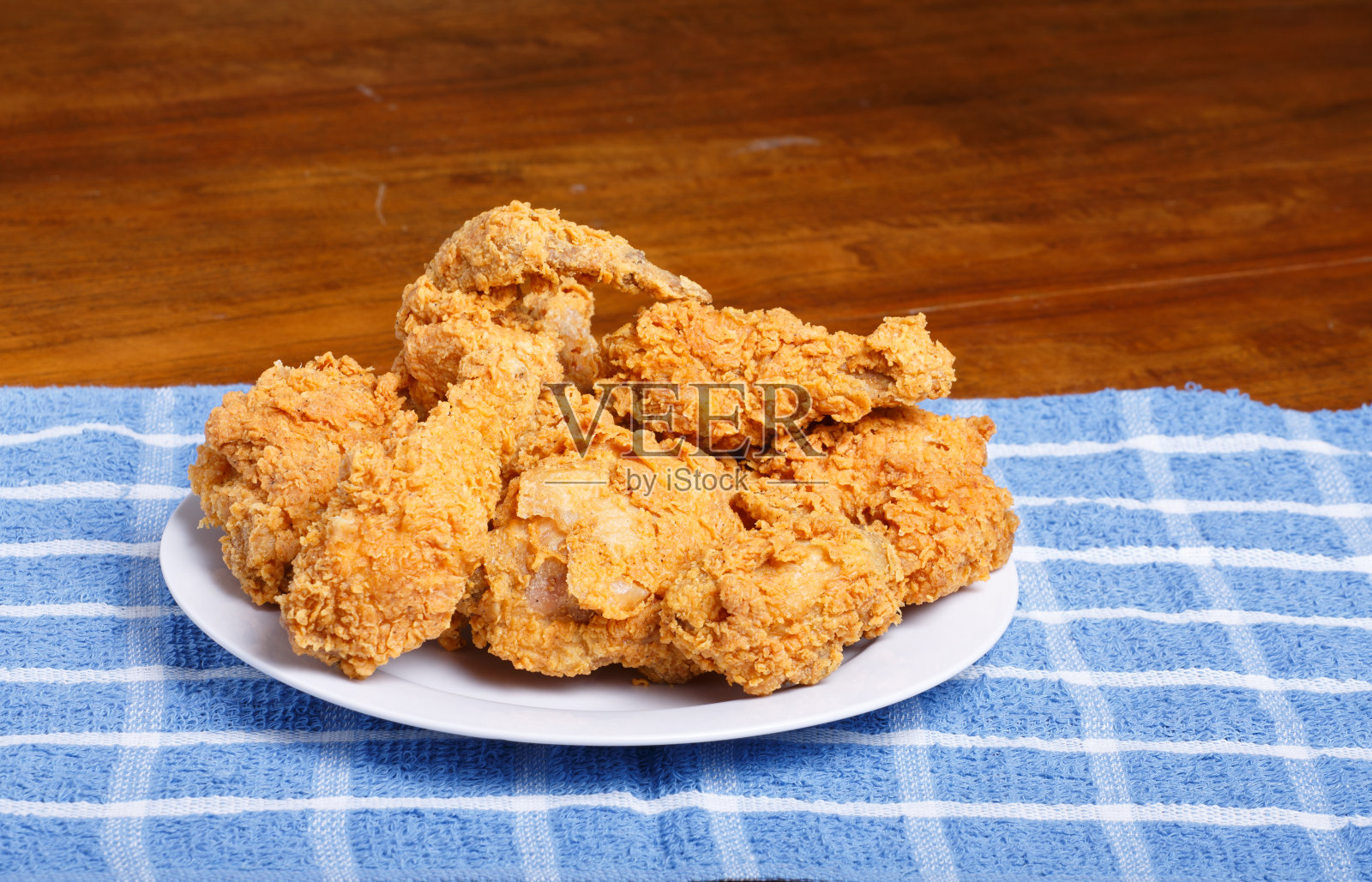 新鲜炸鸡配蓝格子餐垫和木桌照片摄影图片