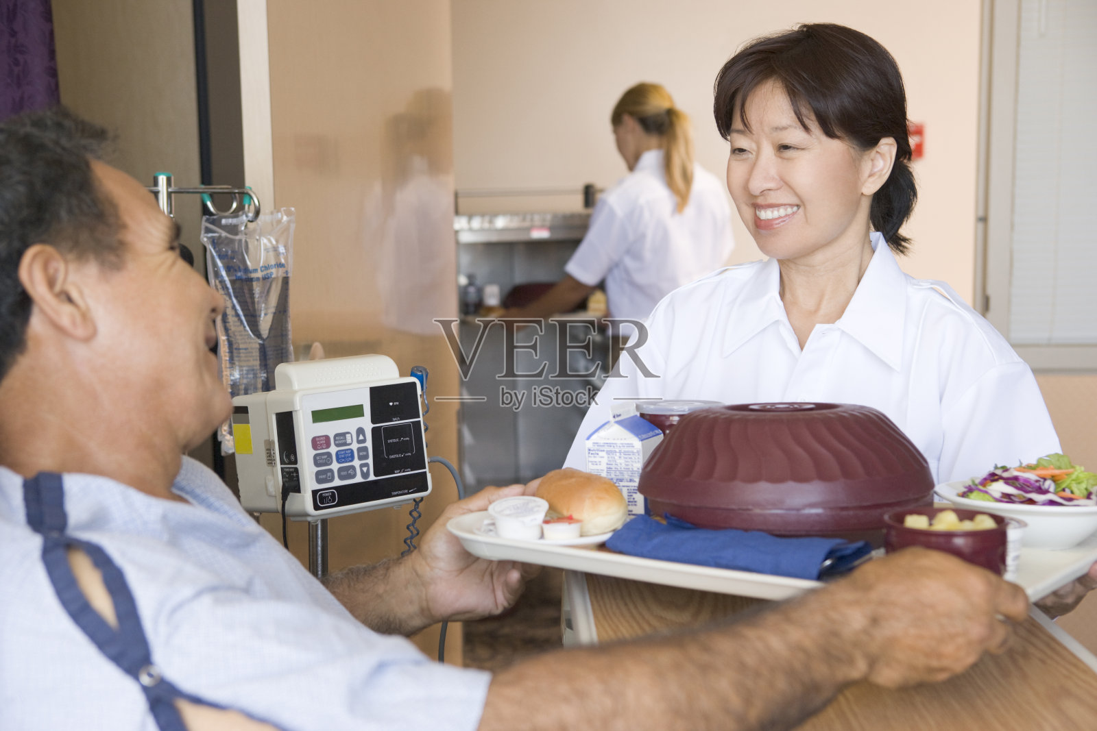 护士在病人的床上给他送饭照片摄影图片