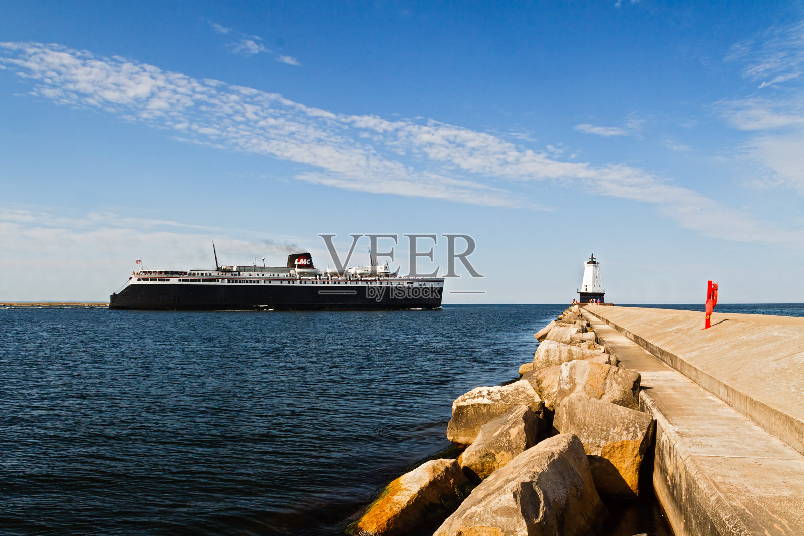 船只经过防波堤上的灯塔照片摄影图片