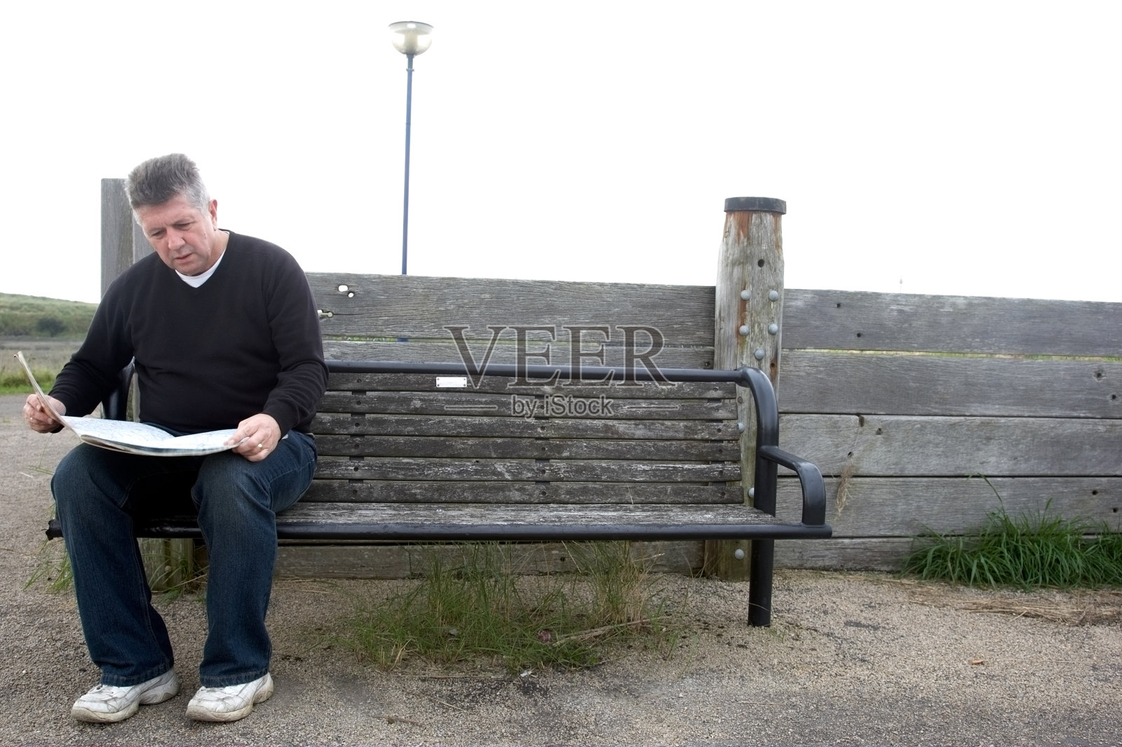 坐在长凳上看地图的男人照片摄影图片