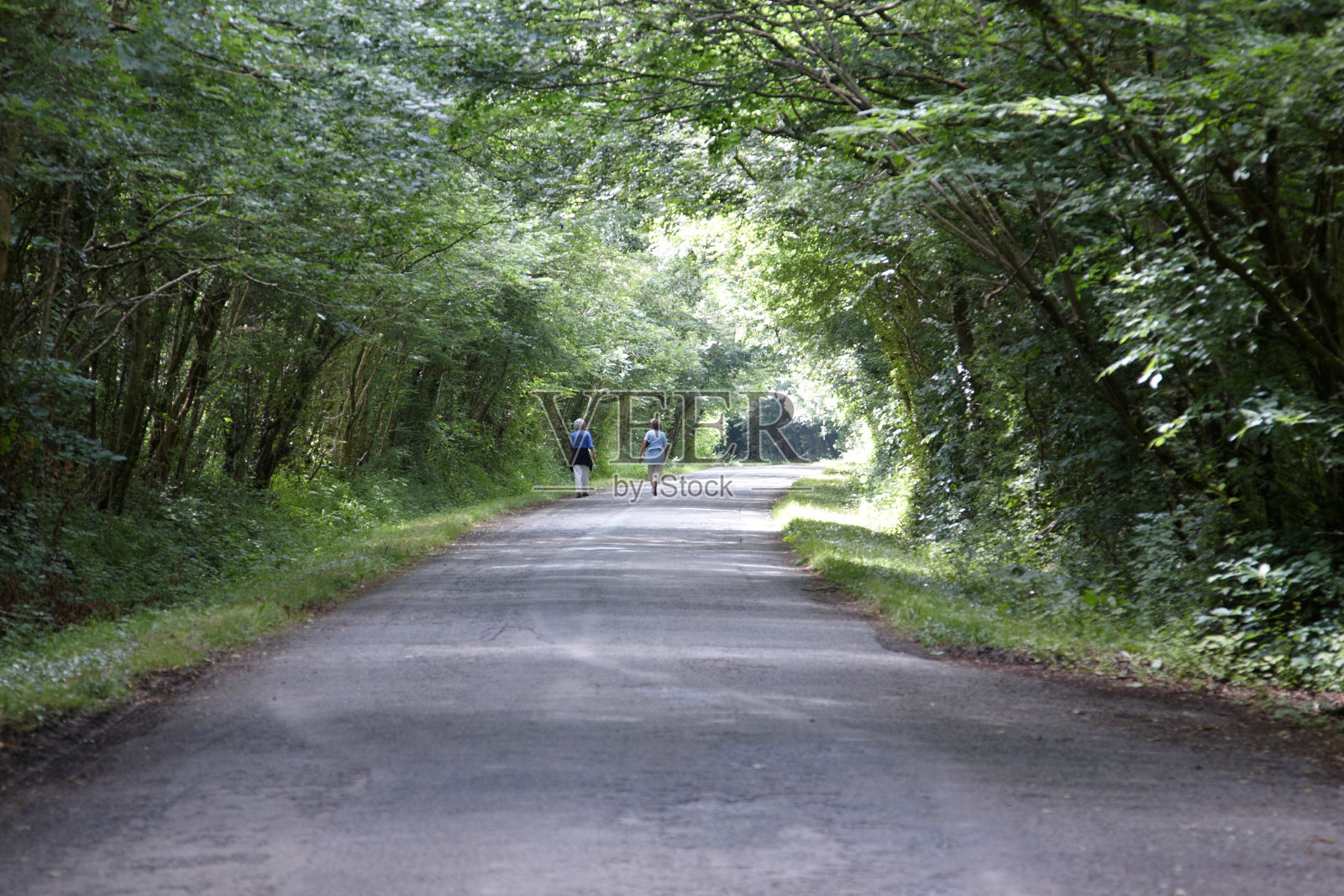 两个女人走过阴凉的乡间小路照片摄影图片