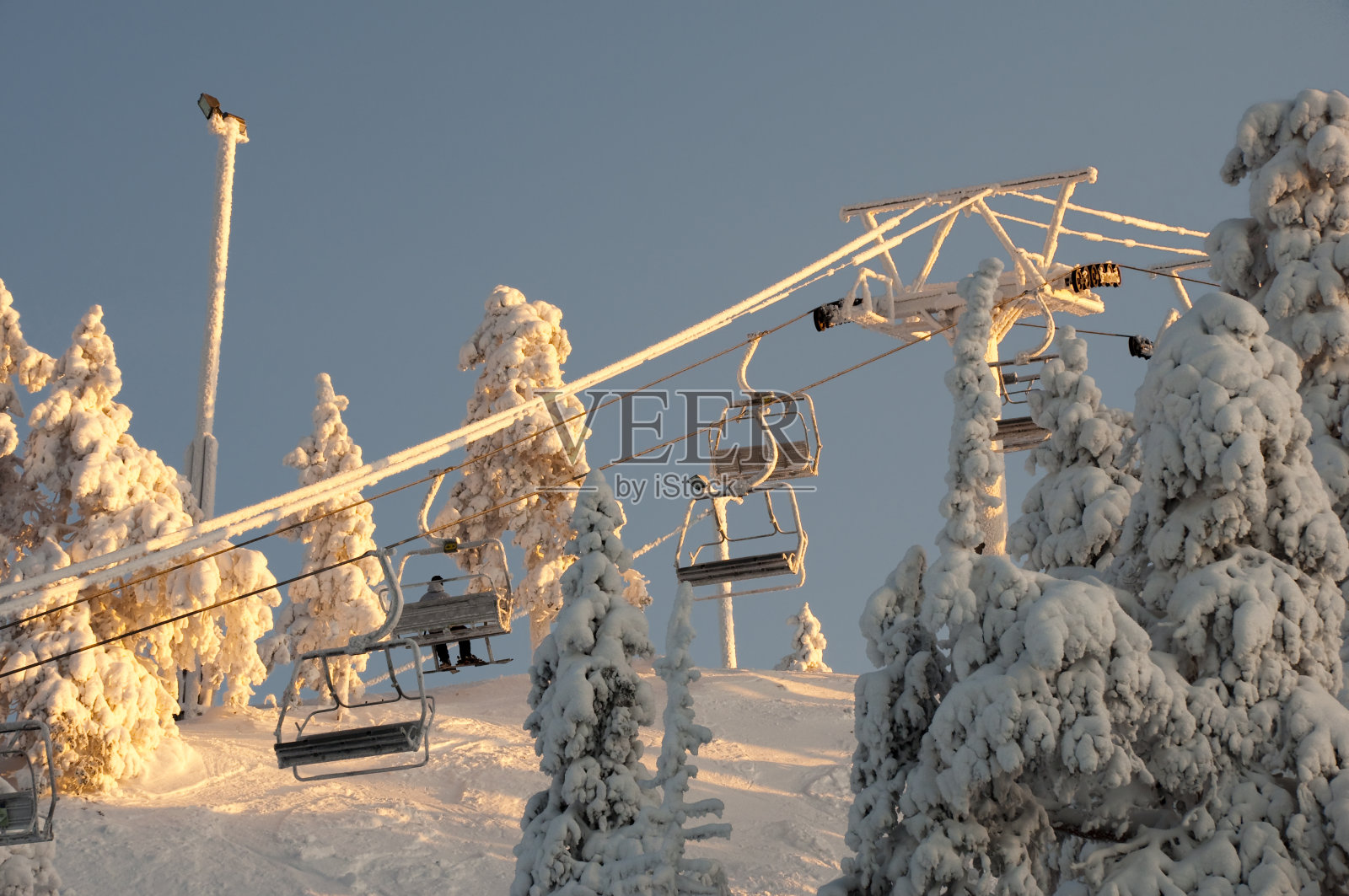 夕阳下覆盖着厚厚的积雪的滑雪缆车照片摄影图片
