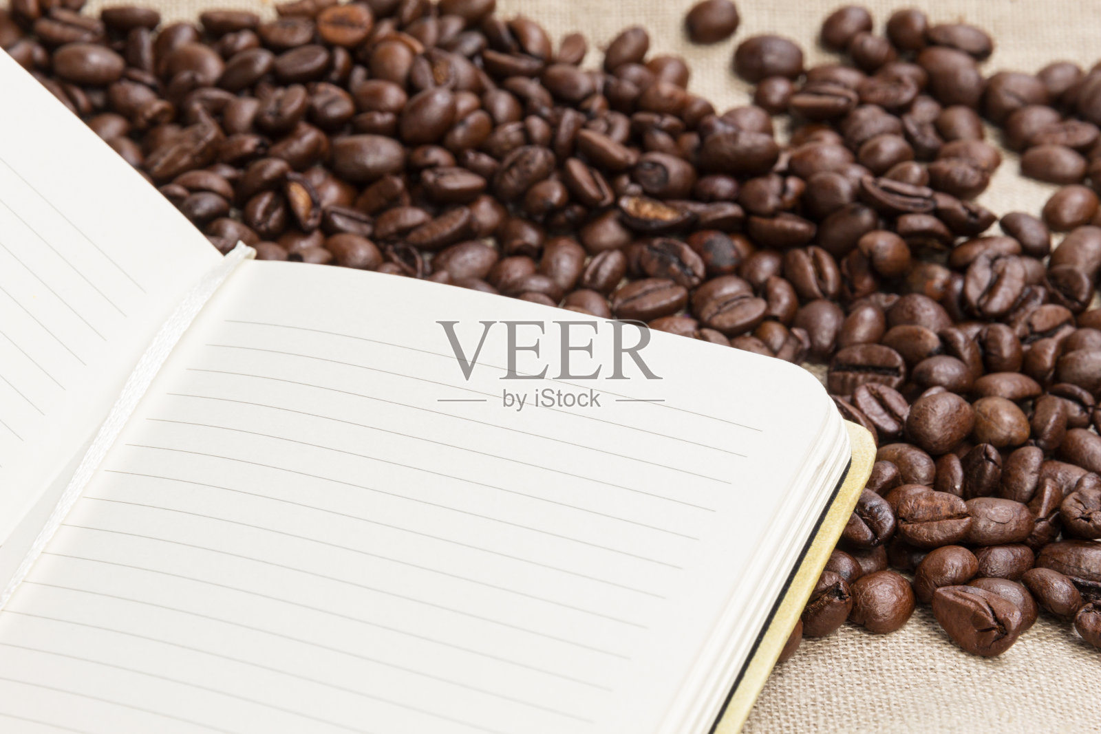 麻袋和记事本上的一堆咖啡豆照片摄影图片