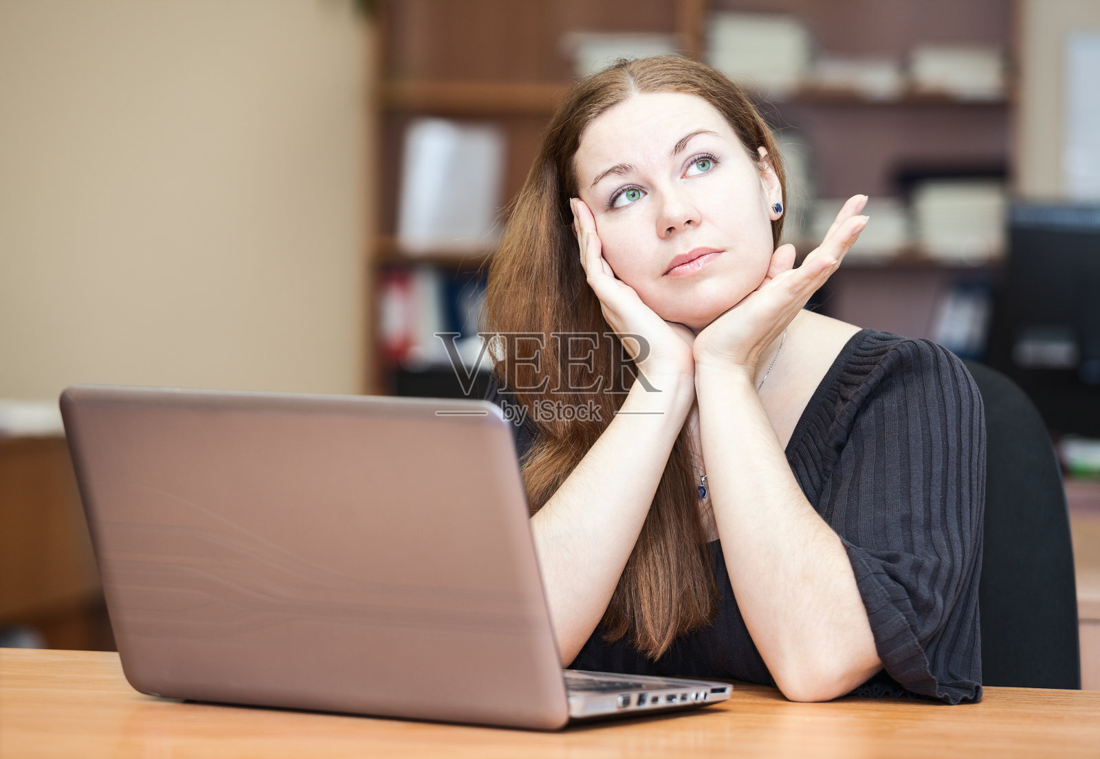 一个深褐色头发的女人在桌前思考照片摄影图片