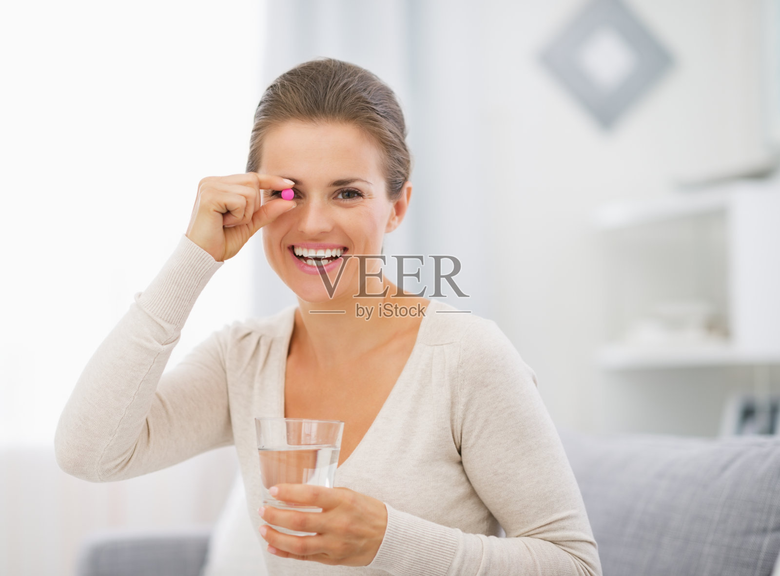 快乐的年轻女子,拿着药丸和一杯水照片摄影图片