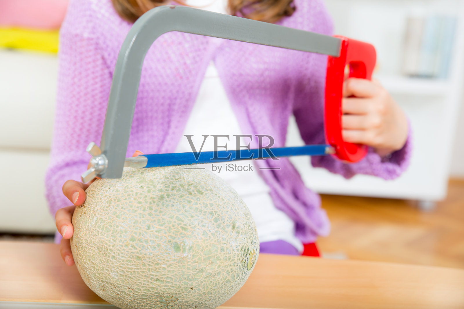 小女孩用锯子切瓜照片摄影图片