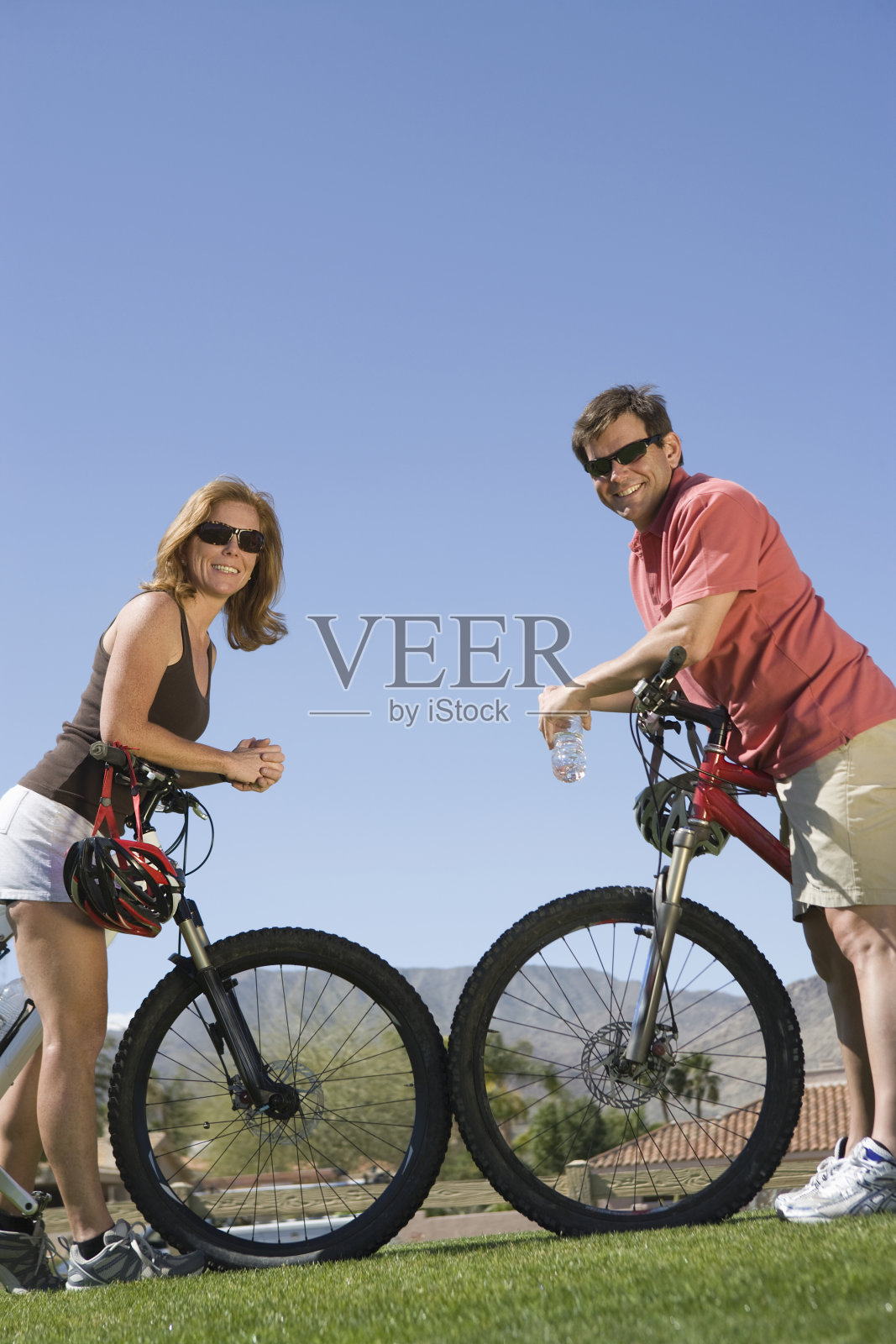 一对情侣倚靠在自行车上,对着蓝天照片摄影图片