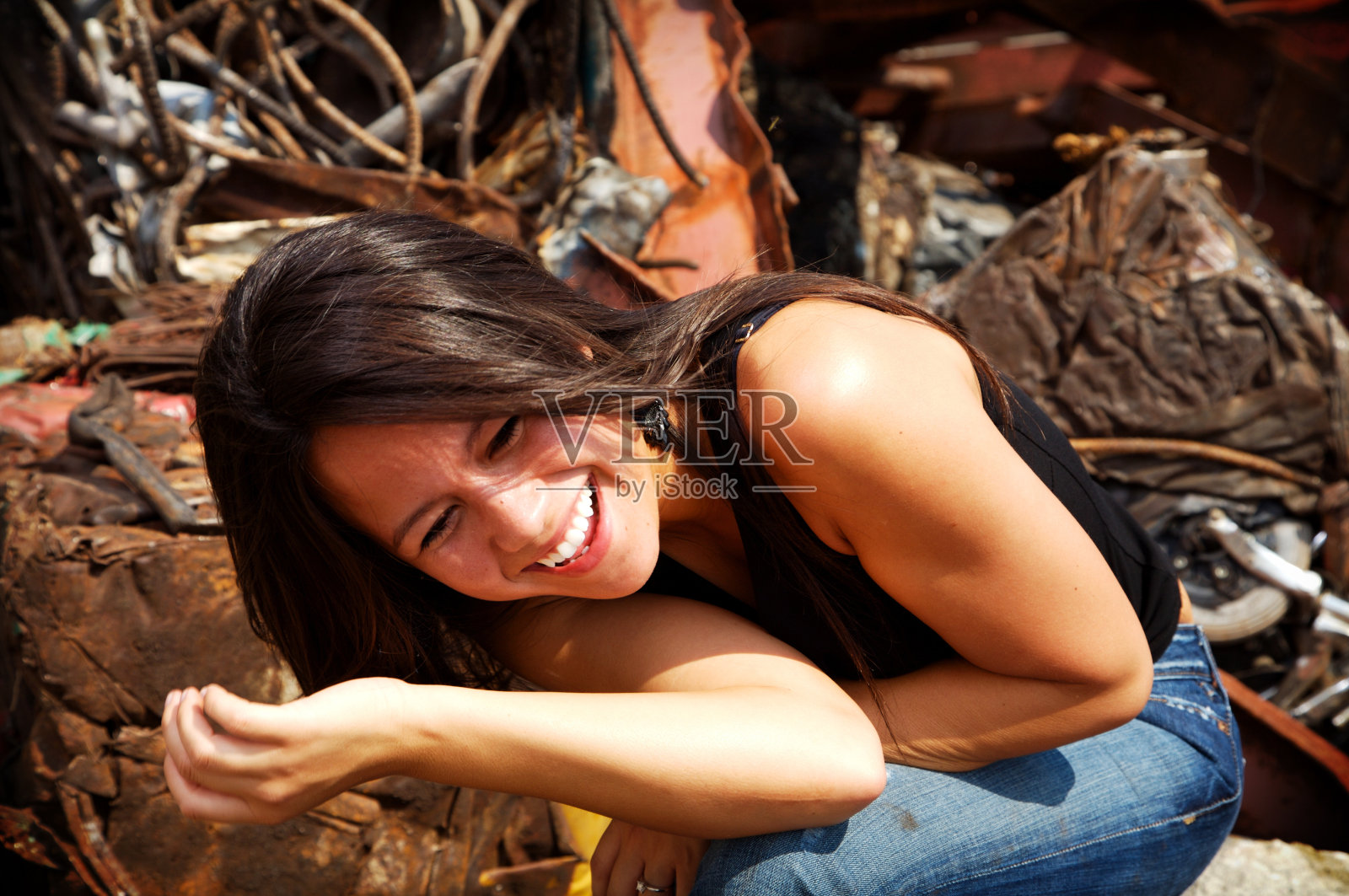 年轻女子笑着坐在一堆垃圾里照片摄影图片