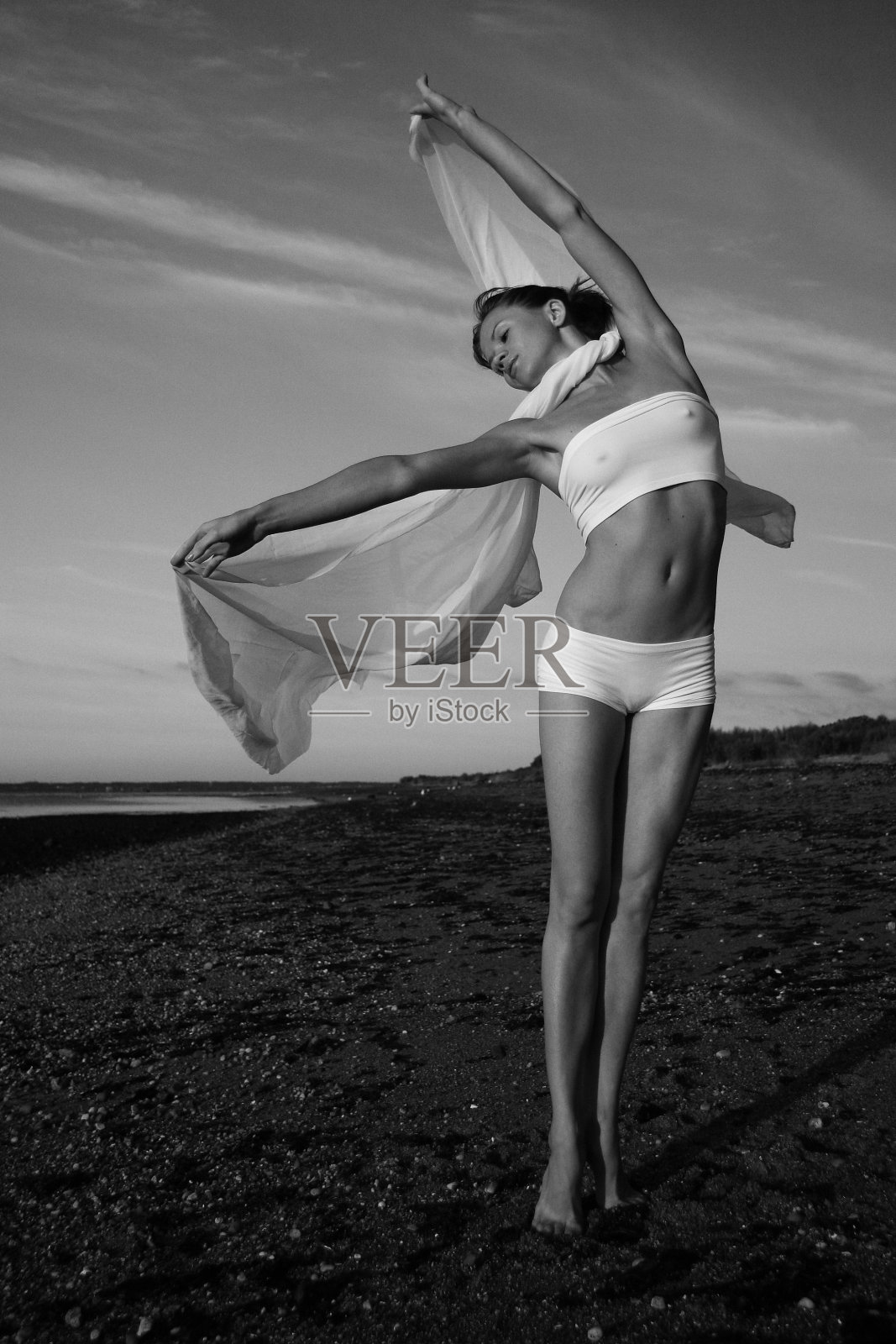 年轻女子体操运动员与围巾在早上的海滩照片摄影图片