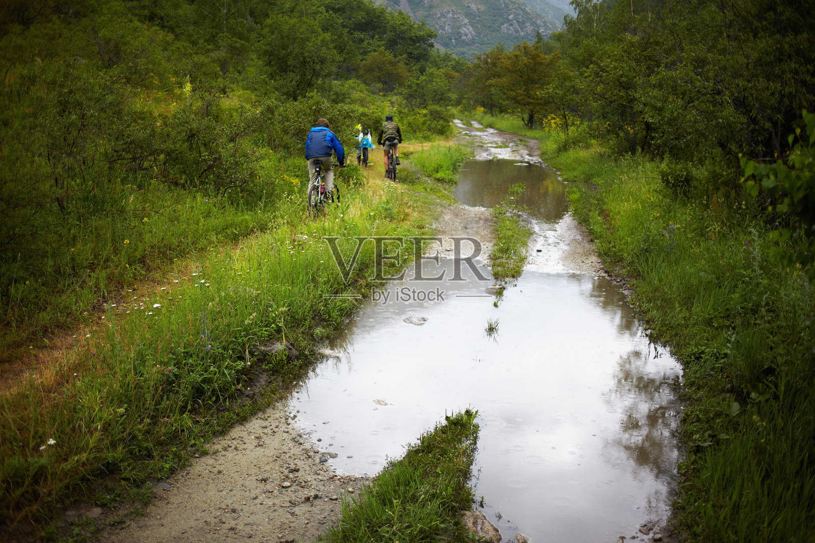 一群山地车在雨中行驶在旧路上照片摄影图片