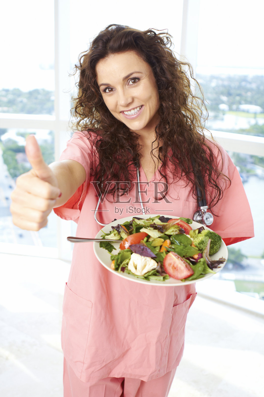 一个护士拿着沙拉竖起大拇指的特写照片摄影图片
