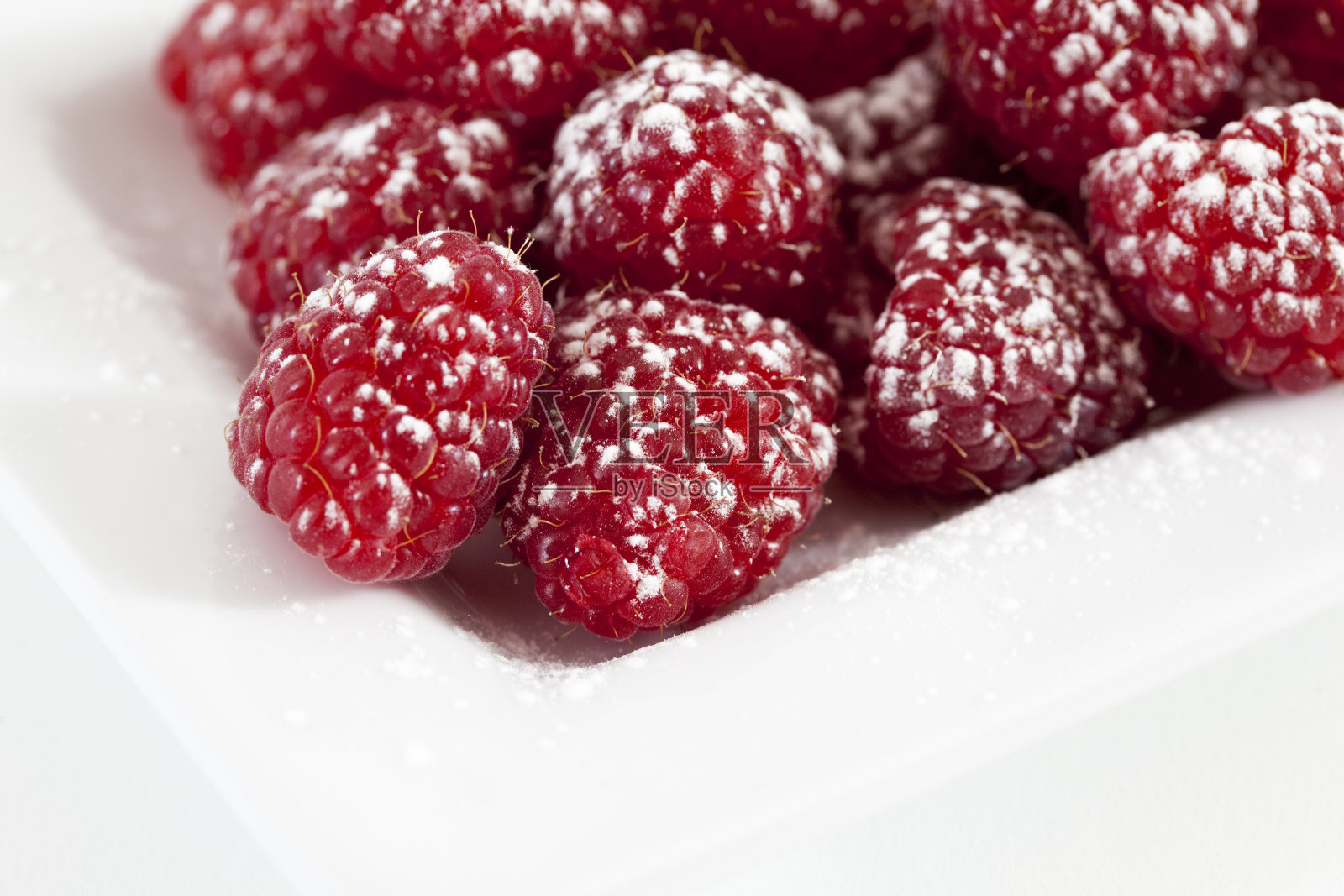 糖粉覆盆子放在白色盘子里照片摄影图片