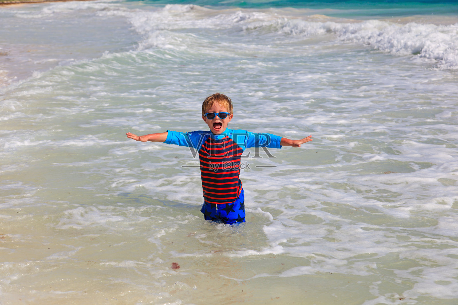 快乐的小男孩在海滩上玩海浪照片摄影图片