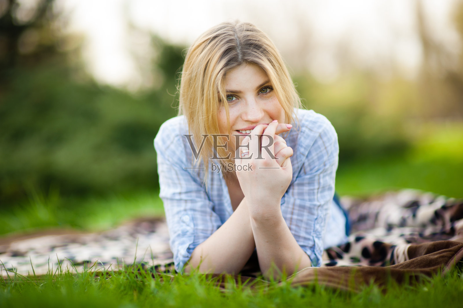 一个美丽的微笑女人的肖像躺在草地上照片摄影图片