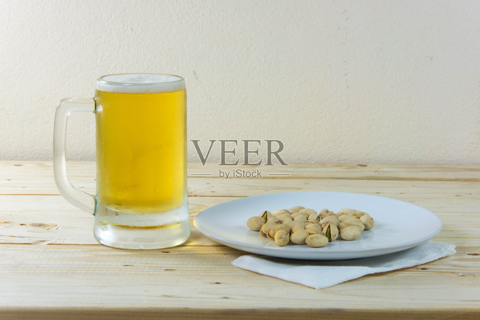 木桌上的静物开心果和玻璃杯里的啤酒照片摄影图片