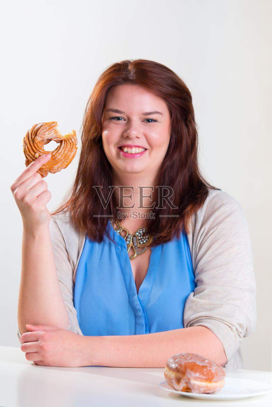 一个胖女人的肖像在桌子上吃着甜甜圈照片摄影图片