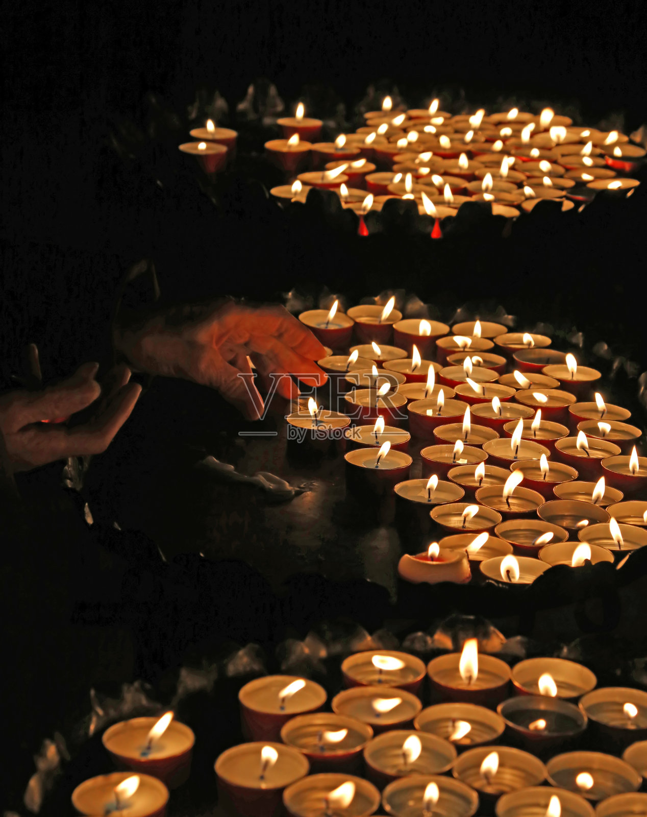 一名妇女在教堂举行弥撒时点燃蜡烛祈祷照片摄影图片
