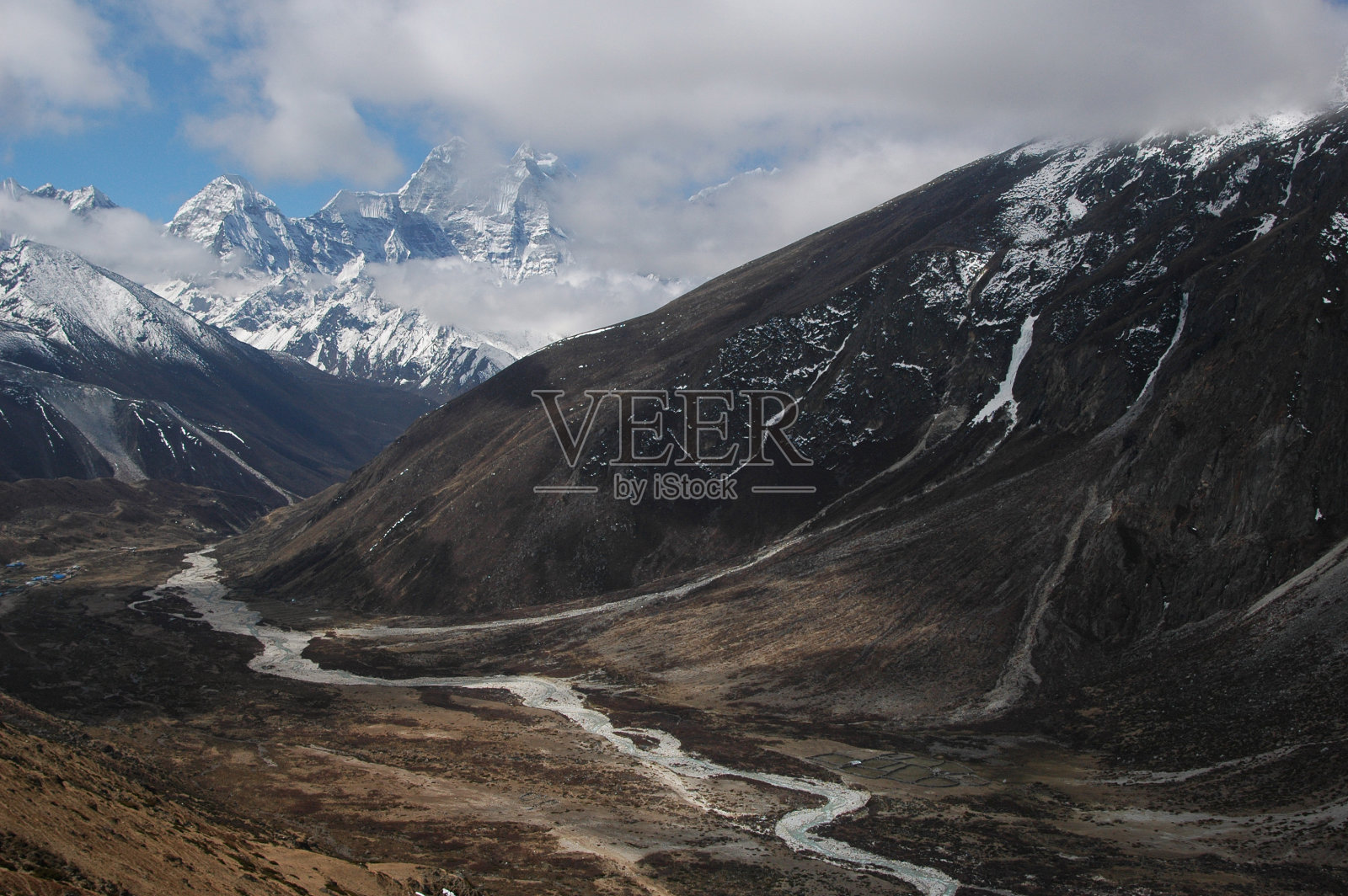 山谷里的一条河,周围都是雪山镐。喜马拉雅山脉。照片摄影图片