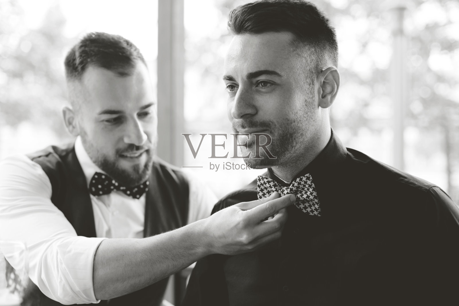 伴郎正在修理新郎的领结照片摄影图片