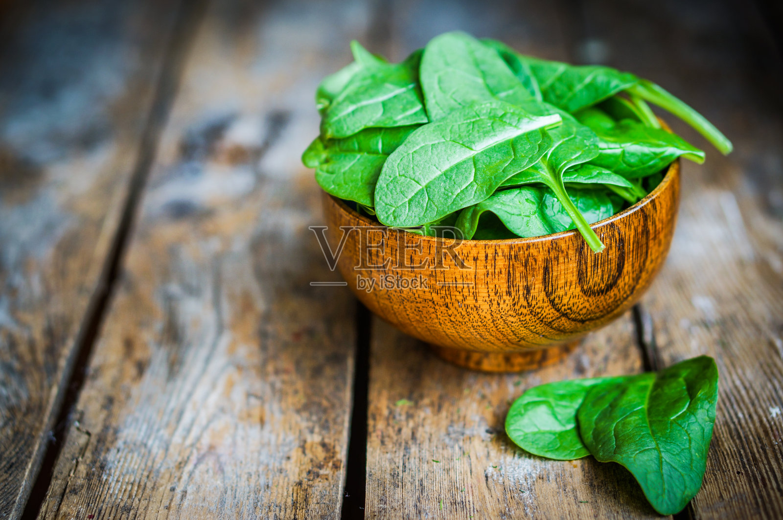 木桌背景上的木碗里装着新鲜菠菜照片摄影图片