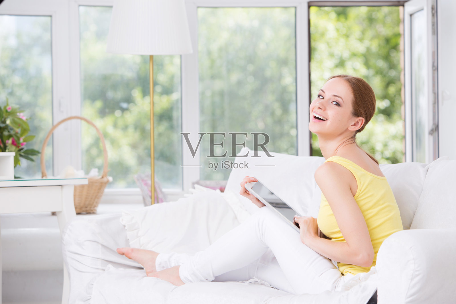 年轻漂亮的女孩坐在沙发上,展示触控板照片摄影图片