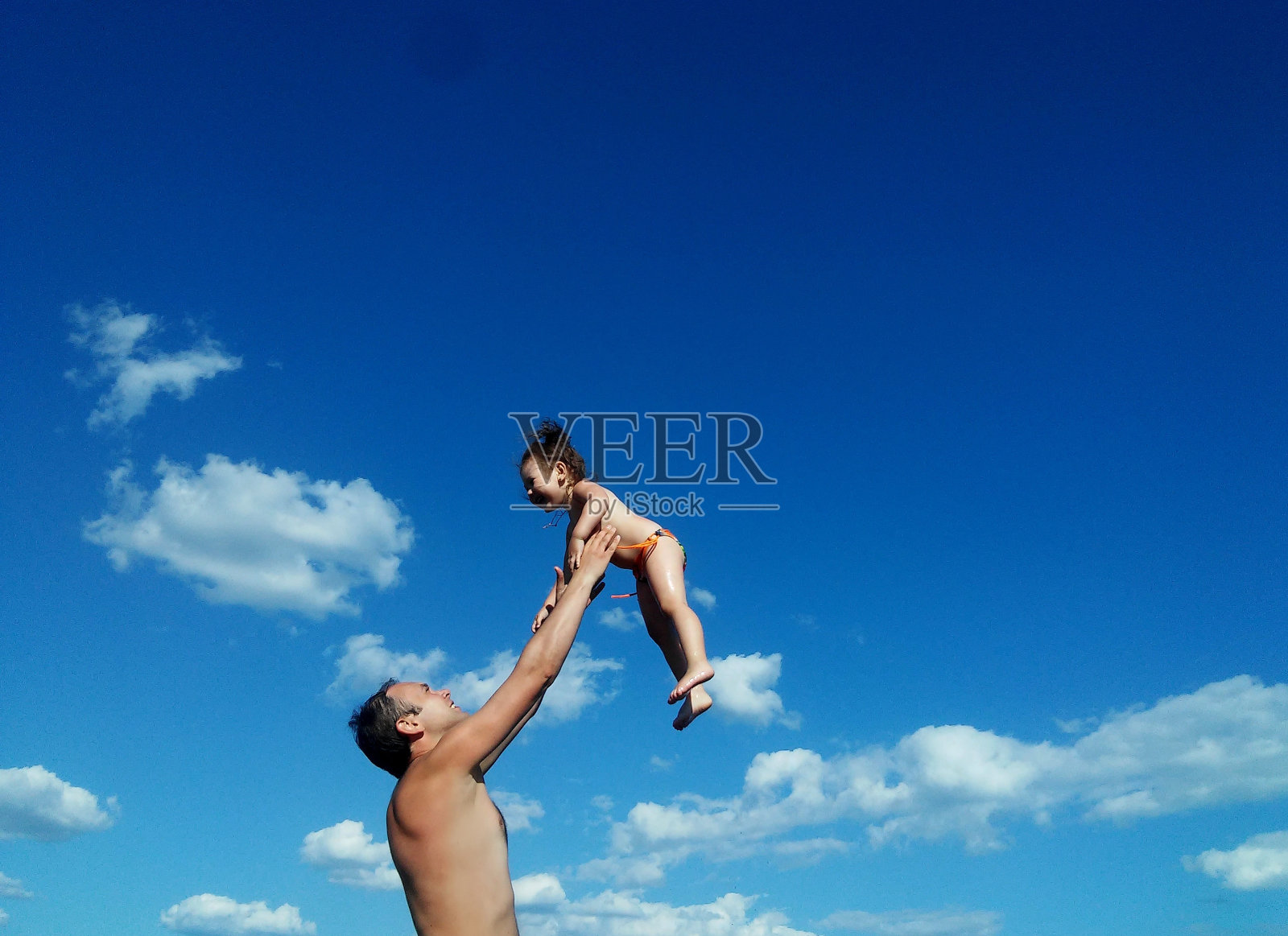 父亲牵着女儿的手,对着天空照片摄影图片