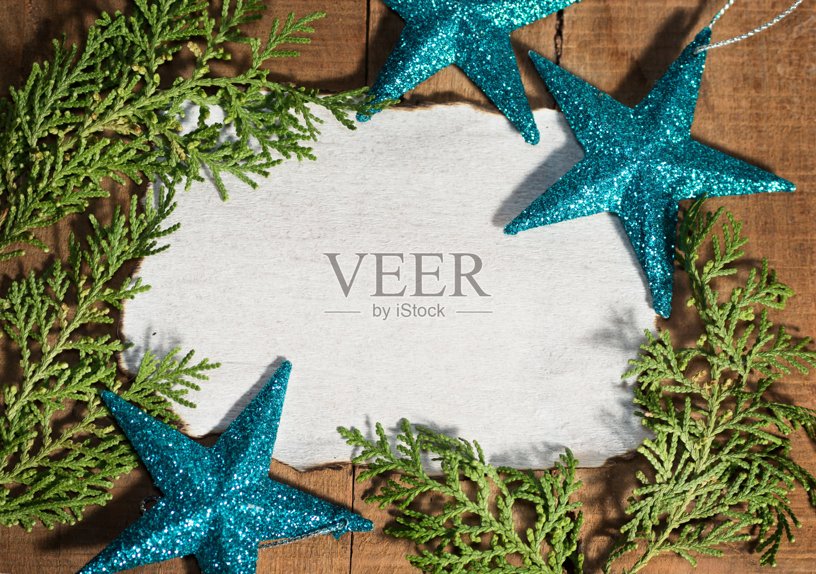 蓝色的星星,绿色的树枝和红色的缎带在烧焦的纸上照片摄影图片