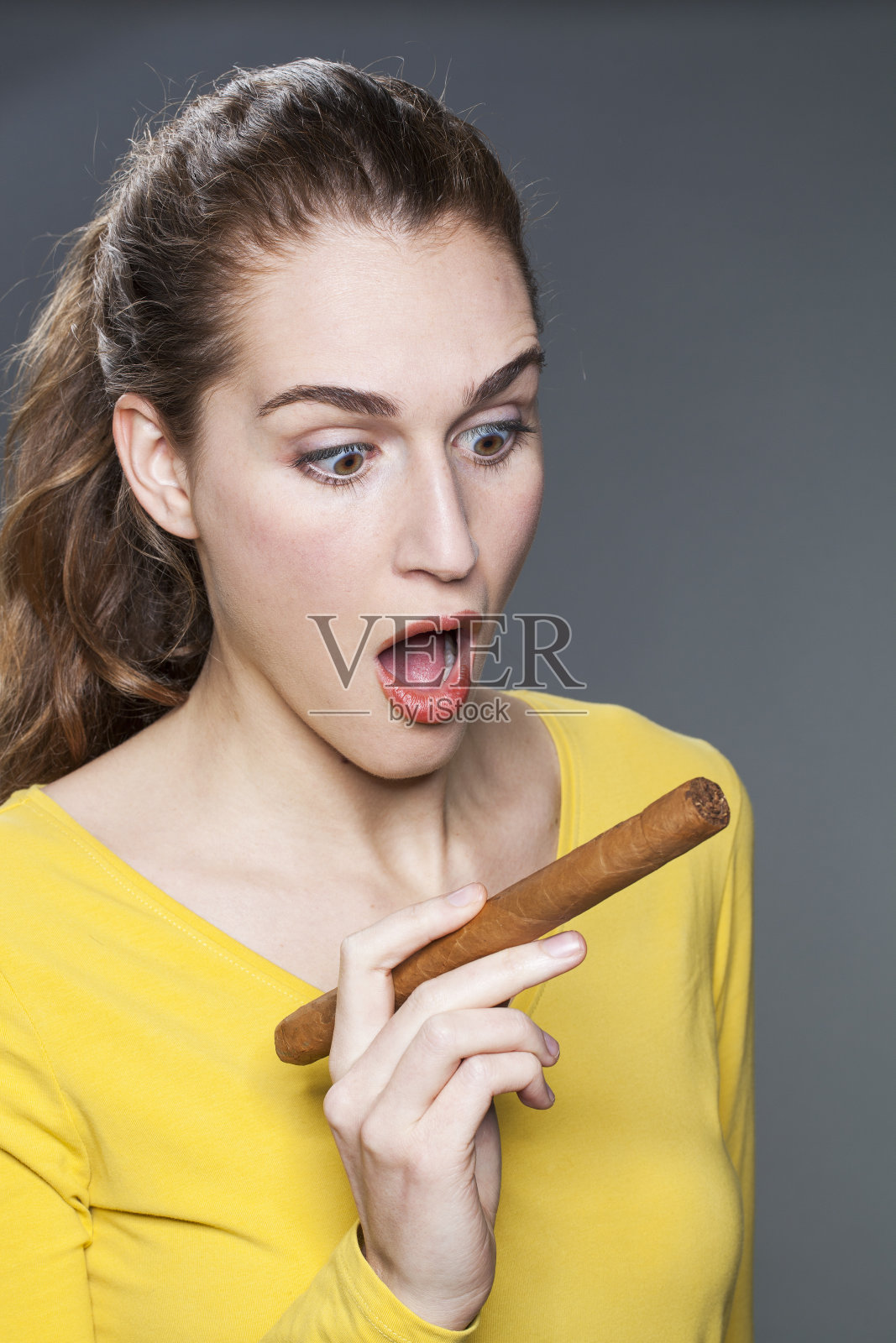 震惊的年轻女子拿着一根大雪茄照片摄影图片