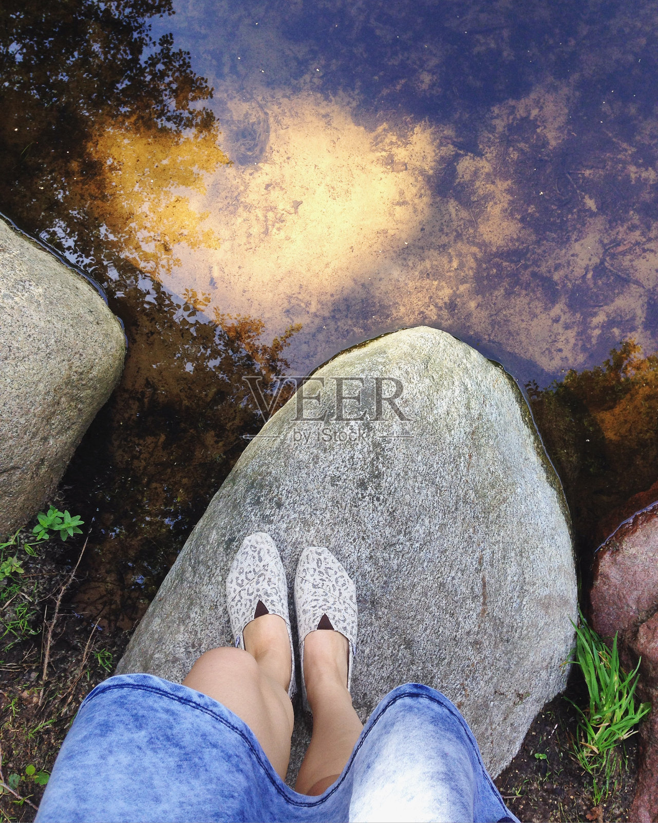 女人的脚踩在湖边的岩石上照片摄影图片