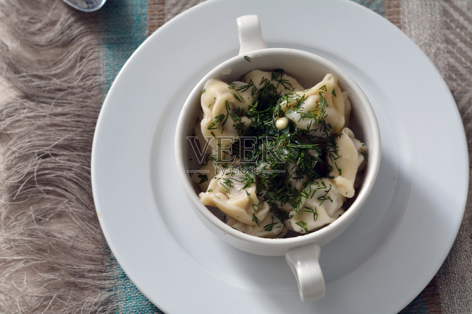 这是一个碗的特写镜头,里面有意大利饺子、融化的黄油和绿色植物照片摄影图片