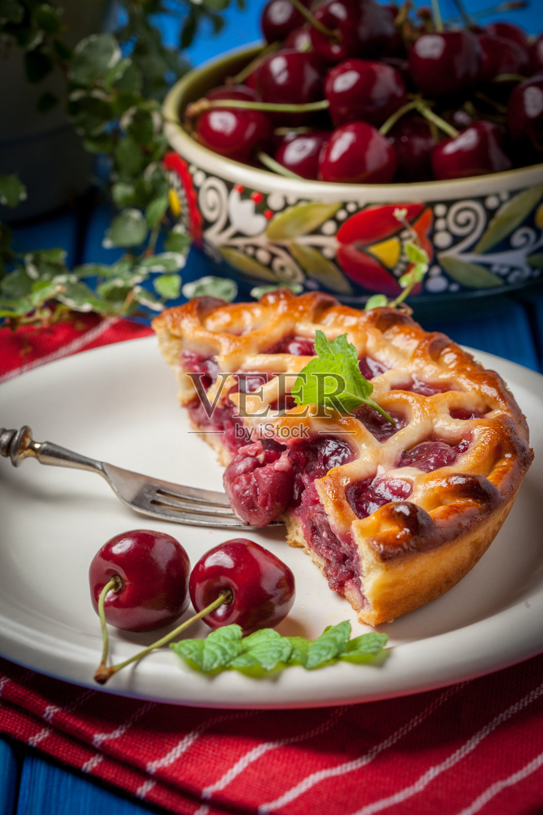 蓝色的桌子上放着自制的樱桃派。照片摄影图片