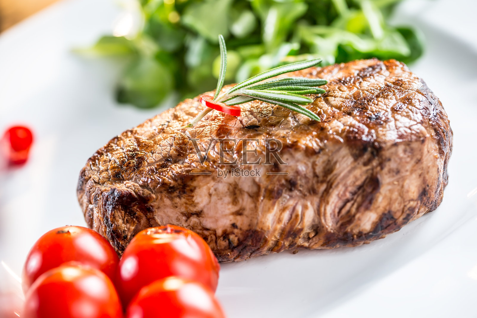 美味牛排配蔬菜和一杯玫瑰葡萄酒。照片摄影图片