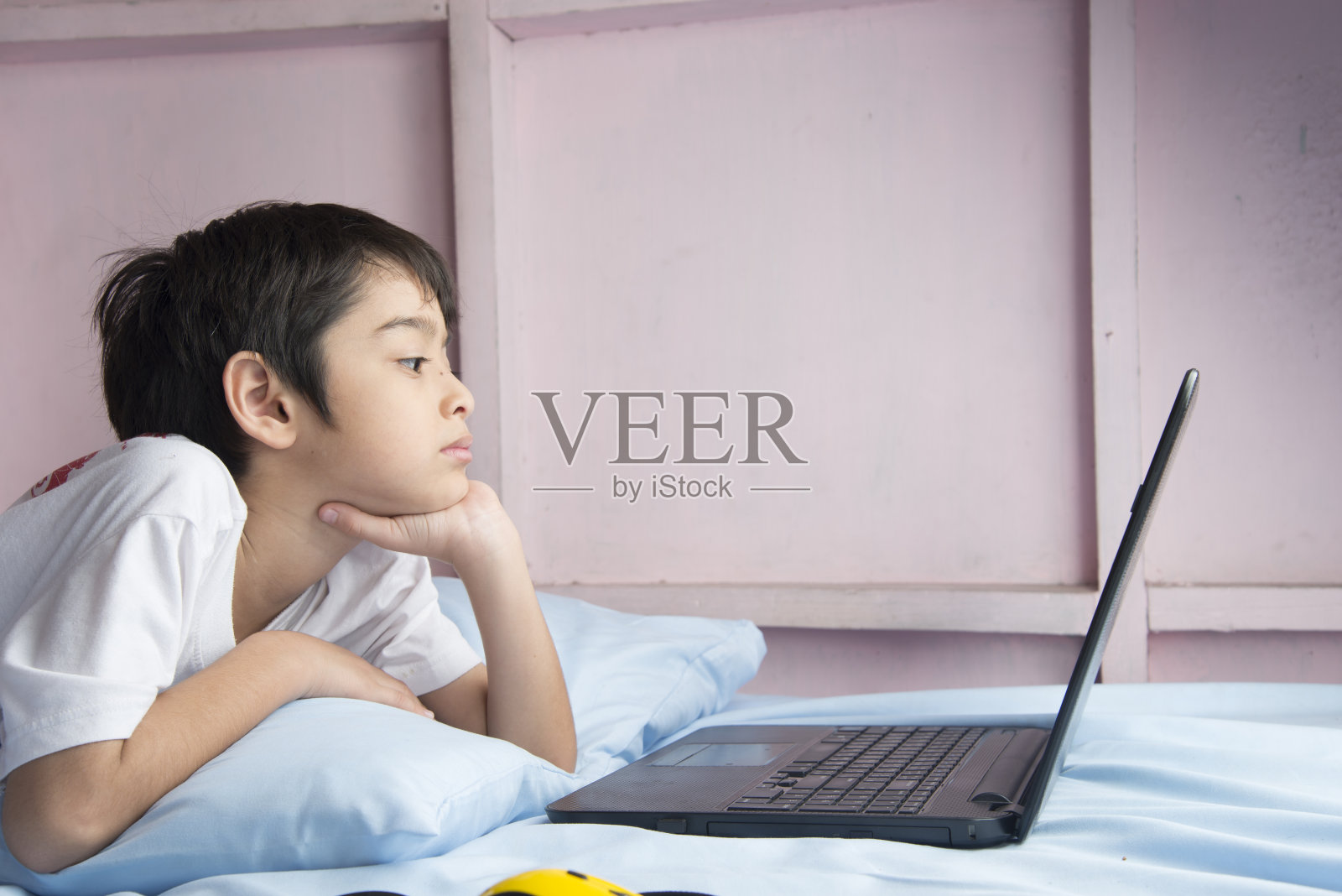 小男孩在卧室里用笔记本电脑照片摄影图片