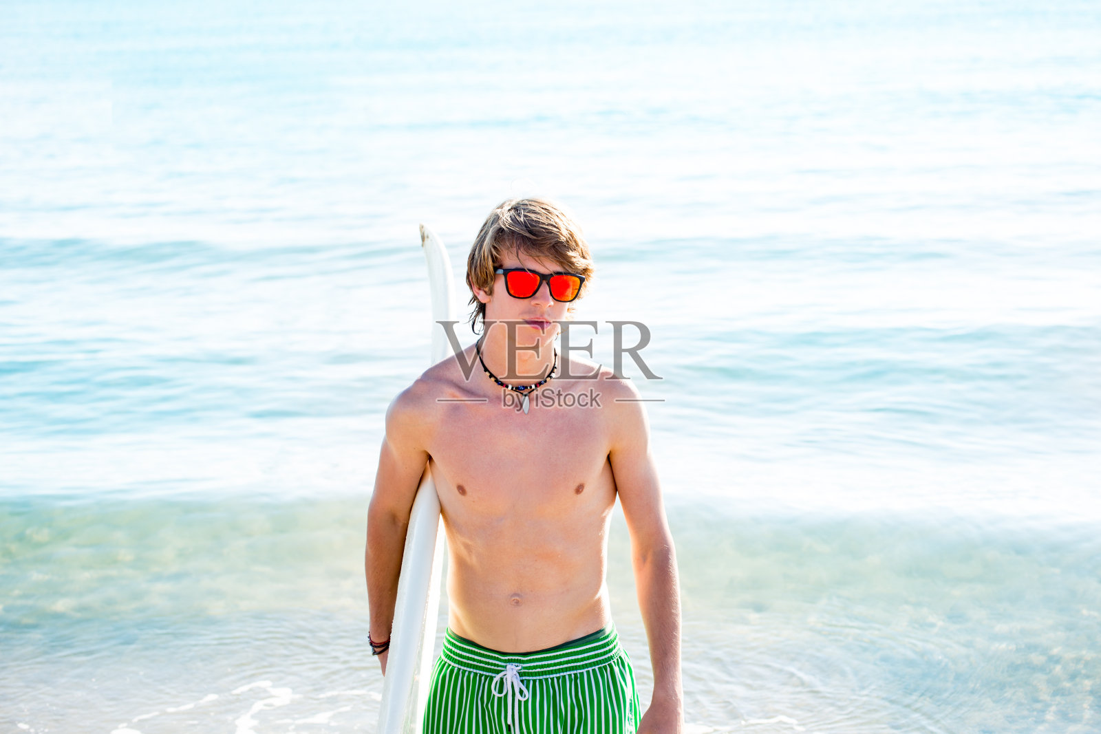 少年与冲浪板在海滩岸边照片摄影图片