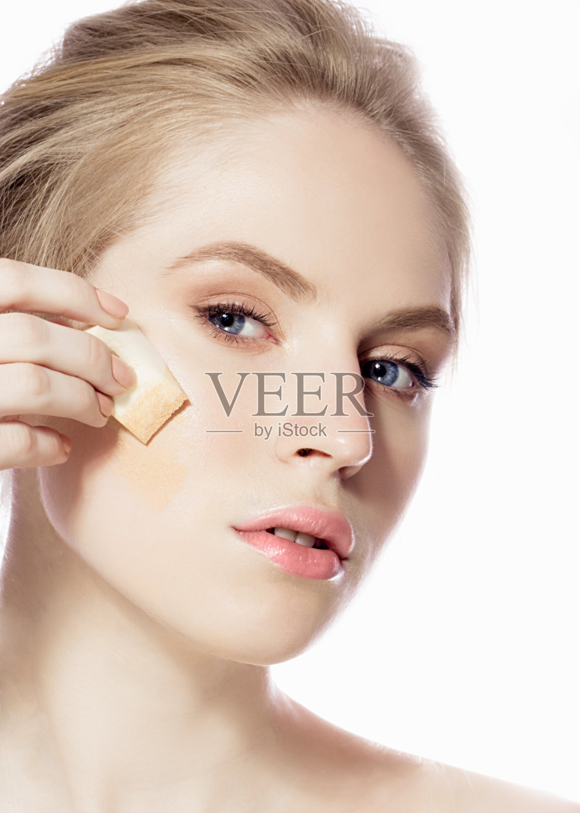 用海绵在脸上敷粉底的女人照片摄影图片