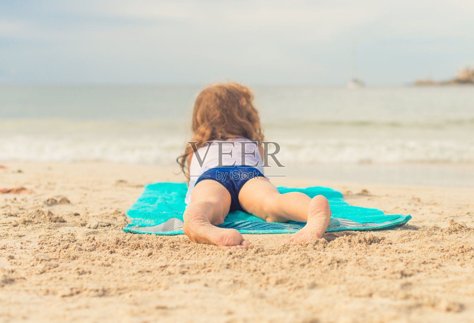 小女孩在沙滩上晒太阳。文本。照片摄影图片