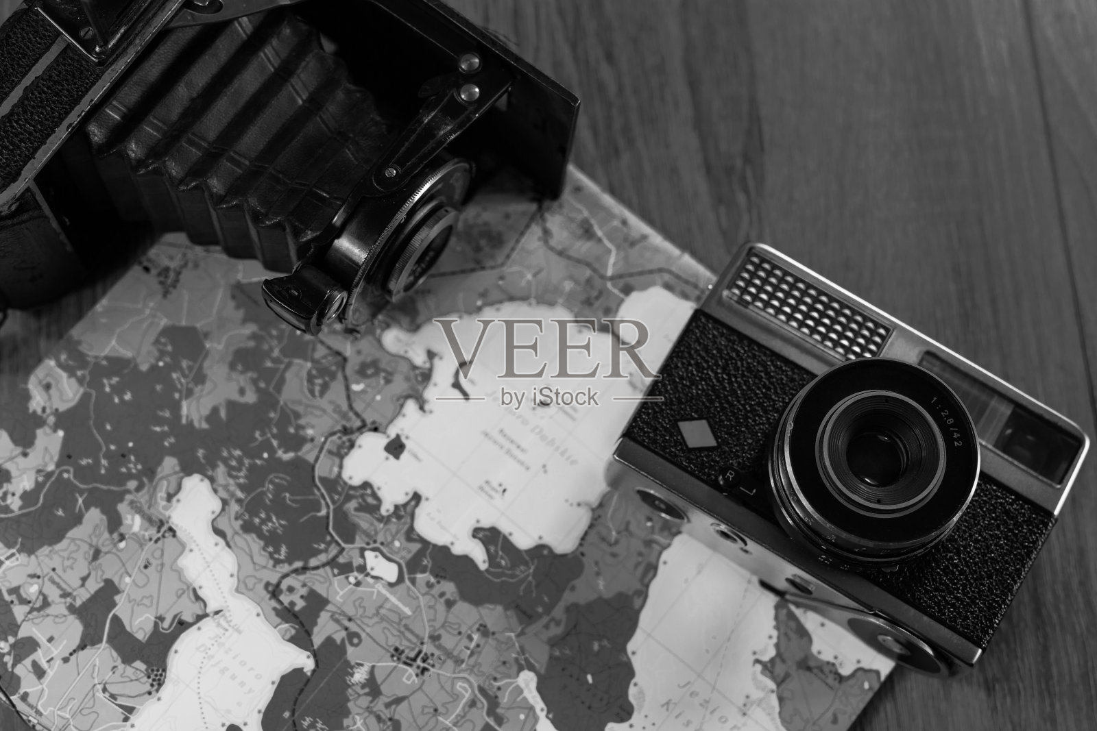 两架旧相机放在纸地图上。黑白照片照片摄影图片