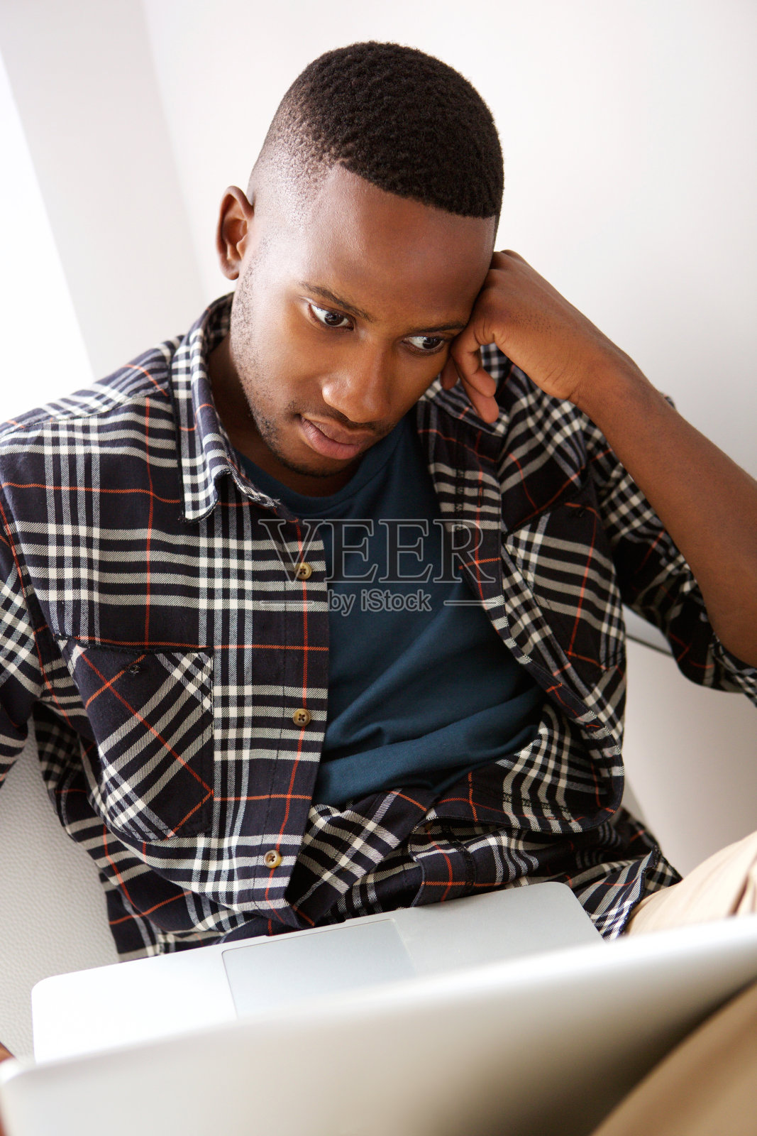 年轻人坐在家里的椅子上看笔记本电脑照片摄影图片