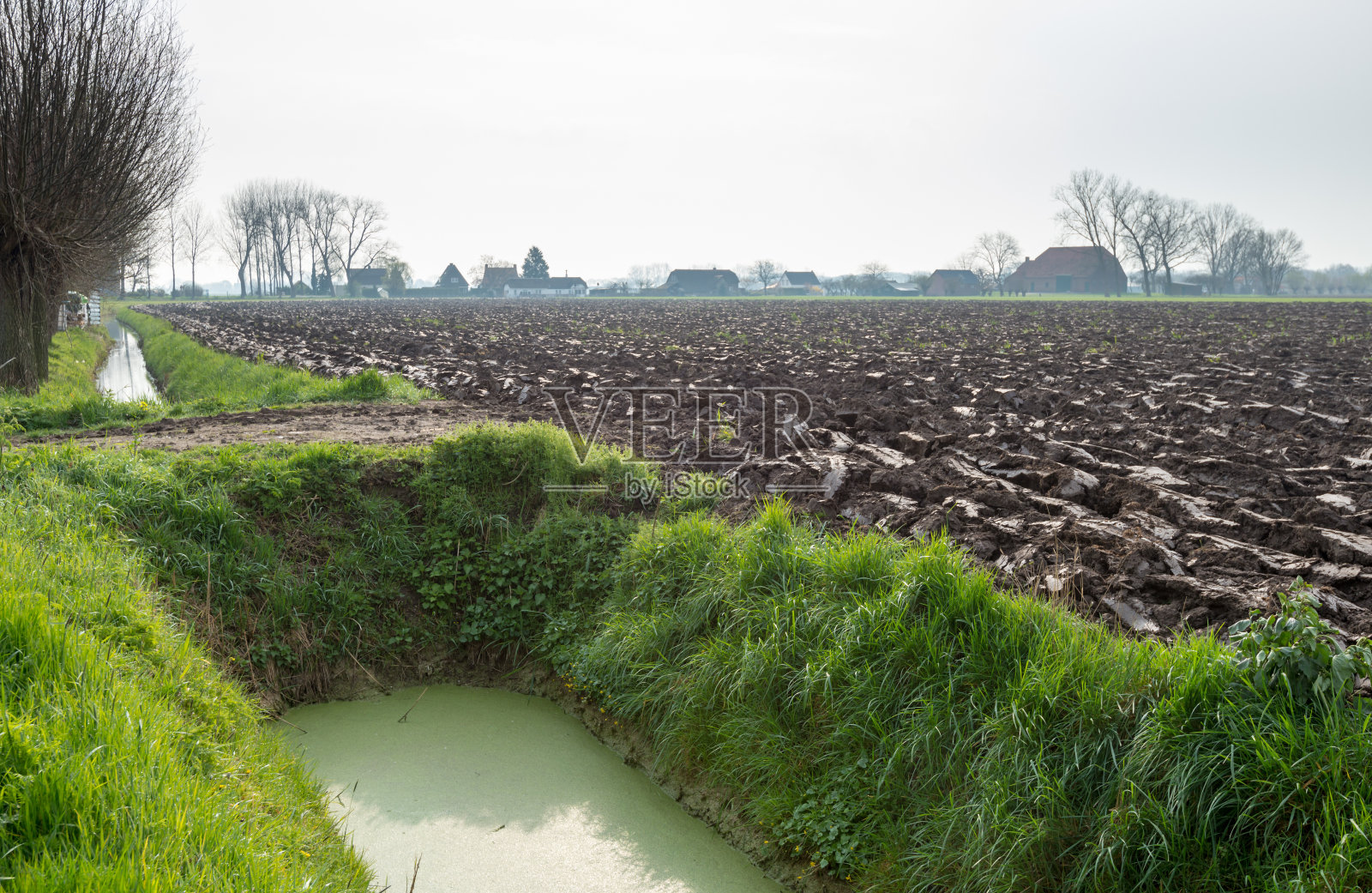最近犁过的田地旁边的一条水沟照片摄影图片