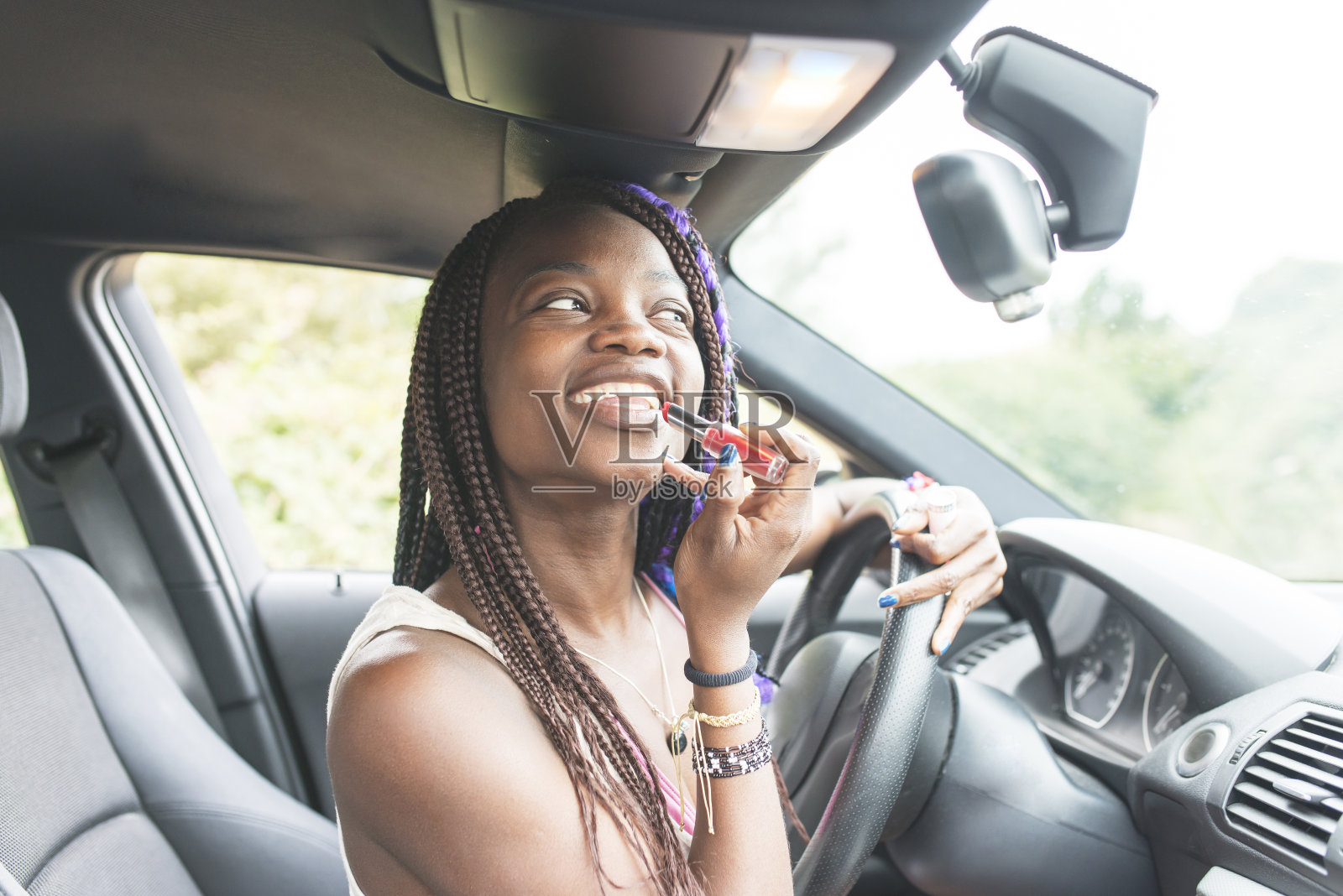 微笑美丽的非洲女人坐在车口红化妆。照片摄影图片