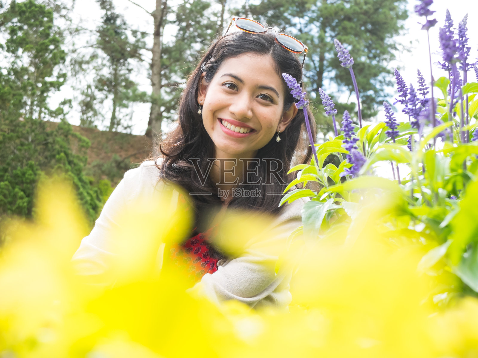 一个女人坐在花园里,前景是黄色的花照片摄影图片
