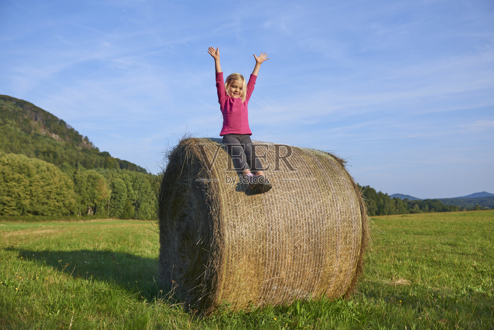 金发碧眼的小女孩在田野里玩稻草捆照片摄影图片