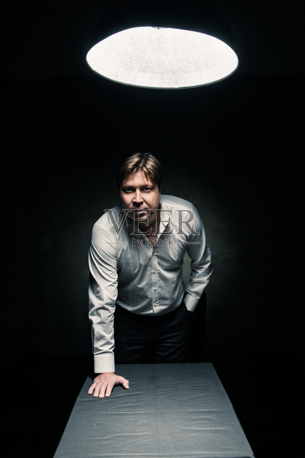 灯光照亮的黑暗房间里的男人照片摄影图片