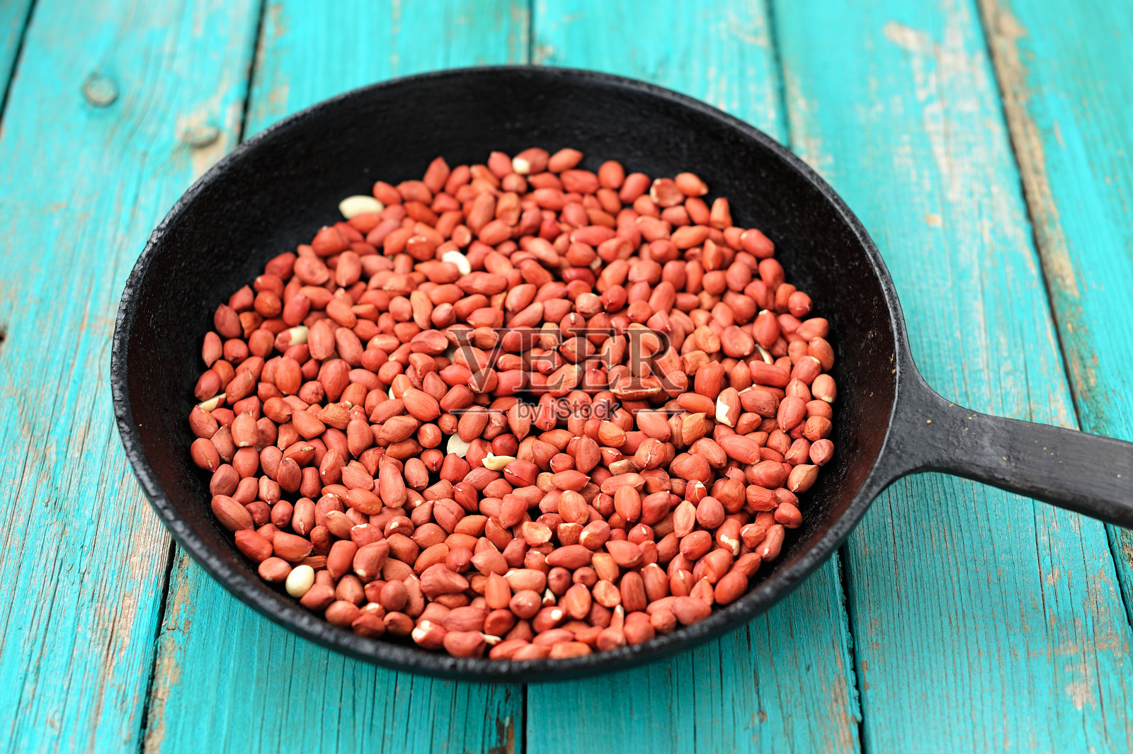 整粒炒花生米放在黑色铸铁锅里照片摄影图片