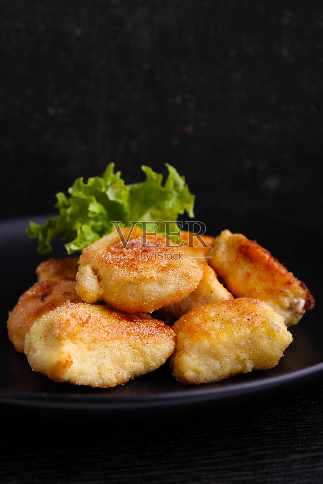 黑色背景的黑色盘子里的鸡块照片摄影图片