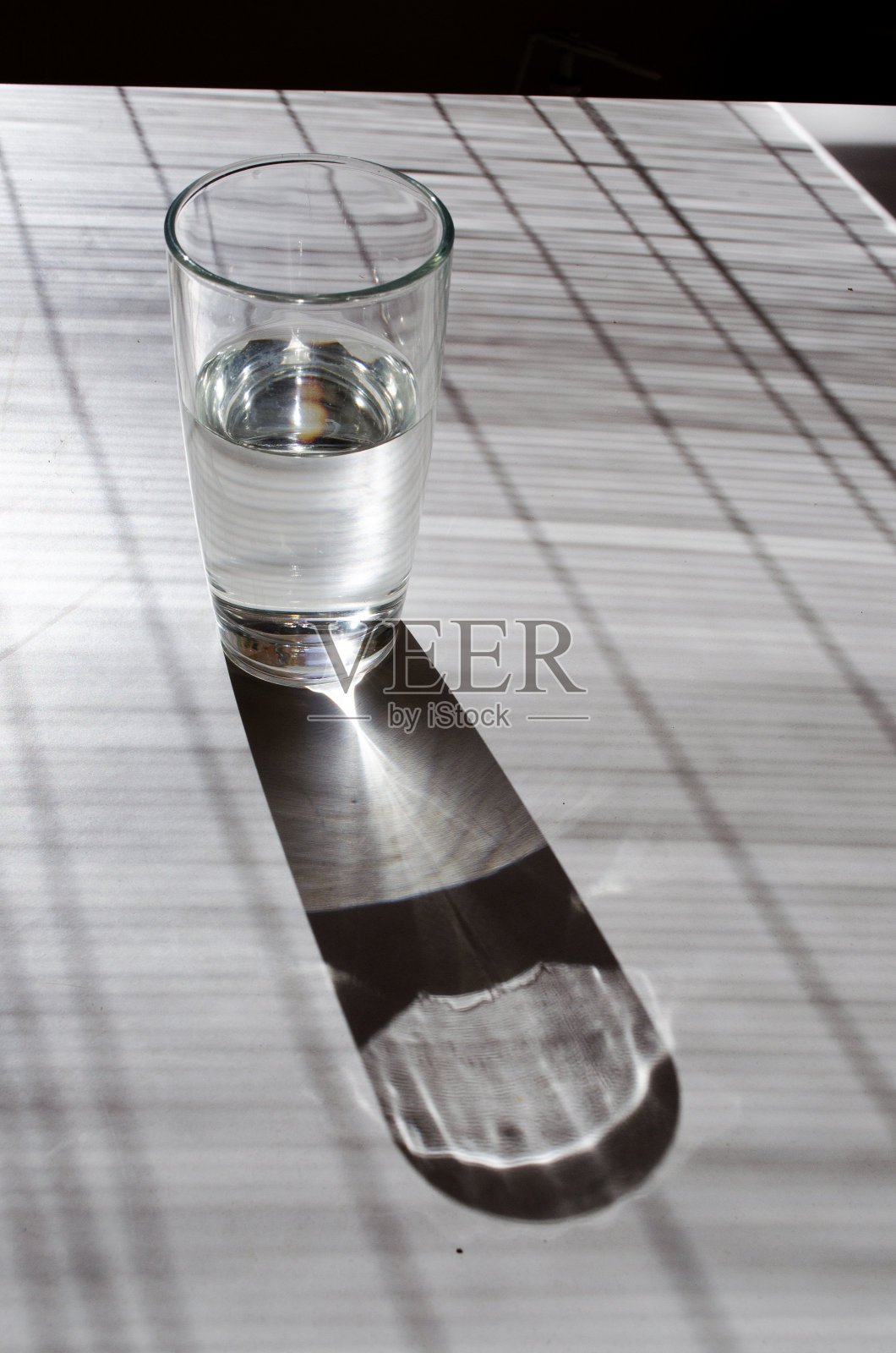 白色的桌子上放着一杯水,在阳光的照射下显得很明亮照片摄影图片