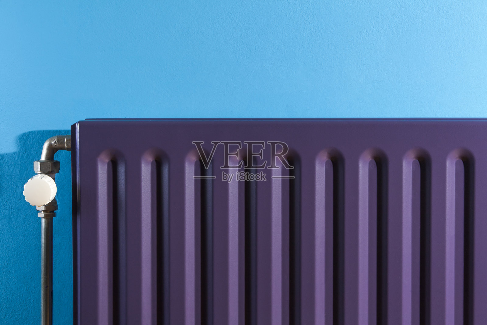 紫色暖气片上的恒温器和蓝色墙壁照片摄影图片