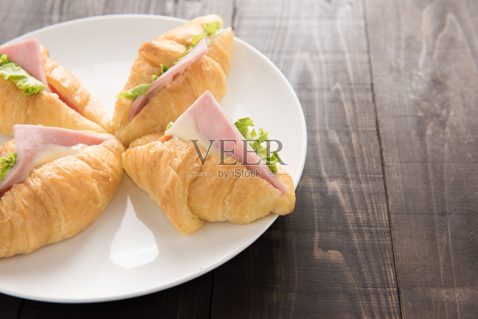 牛角面包,帕尔玛火腿和莴苣放在木桌上照片摄影图片