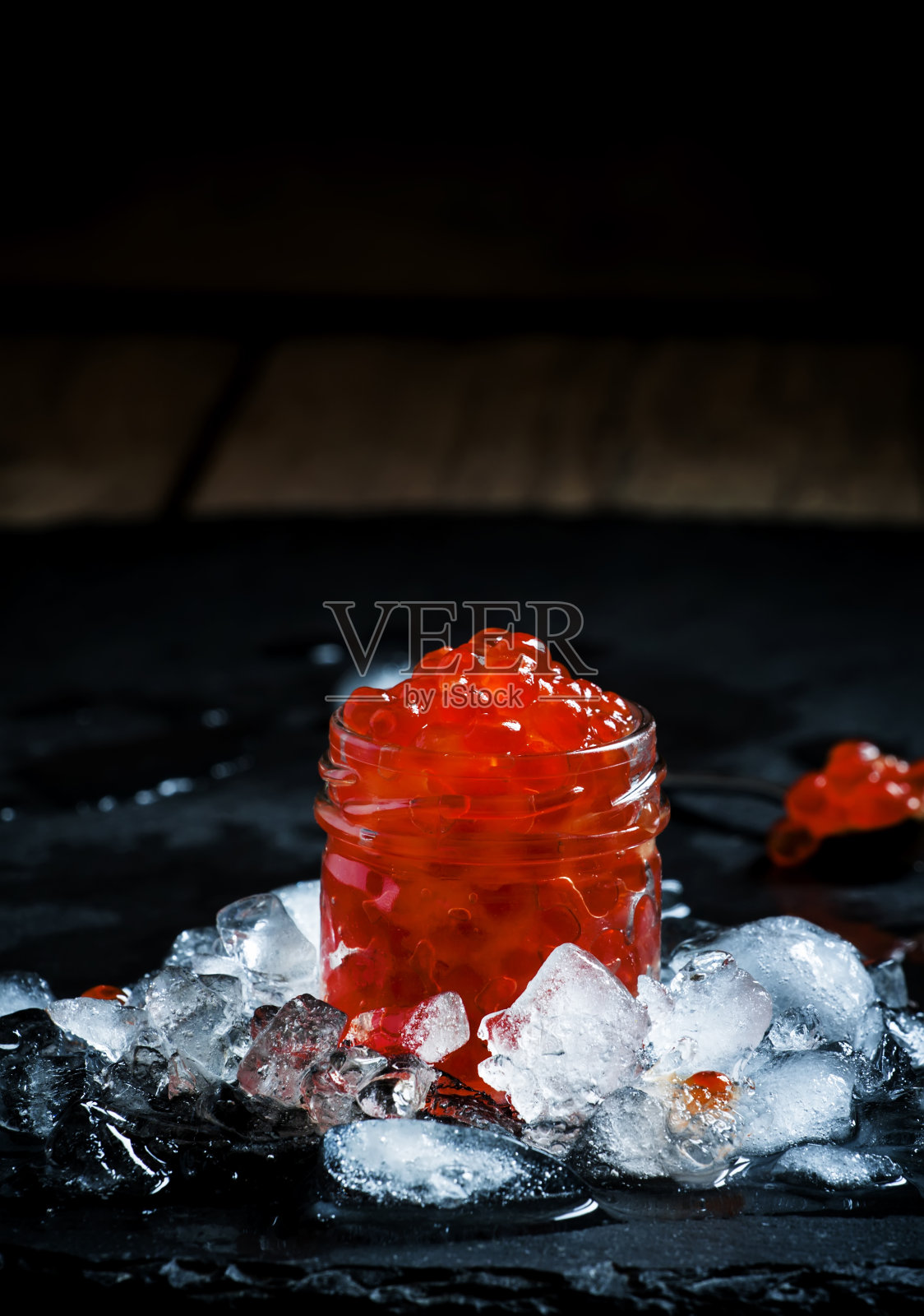 美味的红色鱼子酱放在碎冰上的玻璃罐里照片摄影图片