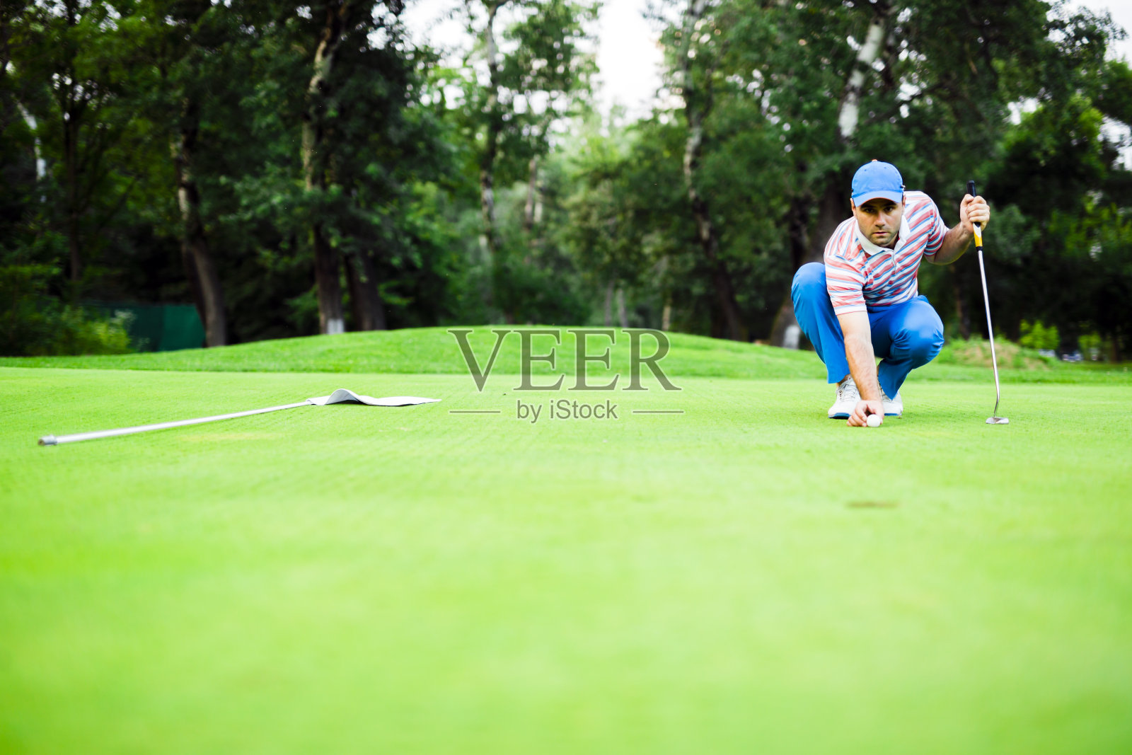 在果岭上标记球的高尔夫球手照片摄影图片